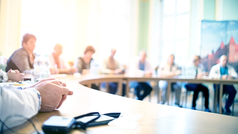 A group of business people attending a meeting sitting at a circular table