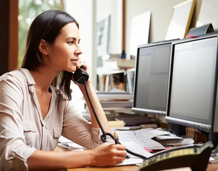 Woman talking on phone looking at computer screen