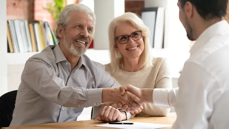 A young man shaking hands with an elderly couple, symbolizing respect and intergenerational connection.