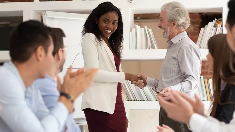 A woman shaking hands with a man and woman in a meeting, showcasing professionalism and collaboration.