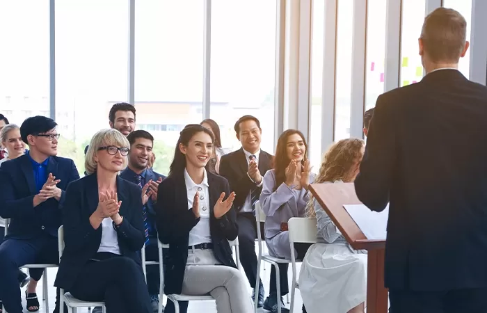 Business professionals applauding at a conference, showing appreciation and support for the speaker.